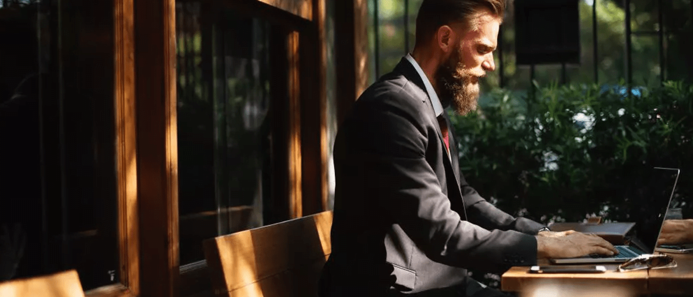A man sat outside in a suit working on a laptop