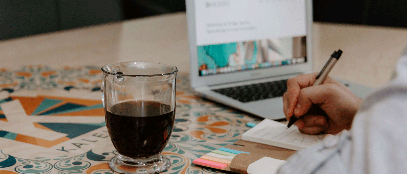 person using laptop and making notes on paper
