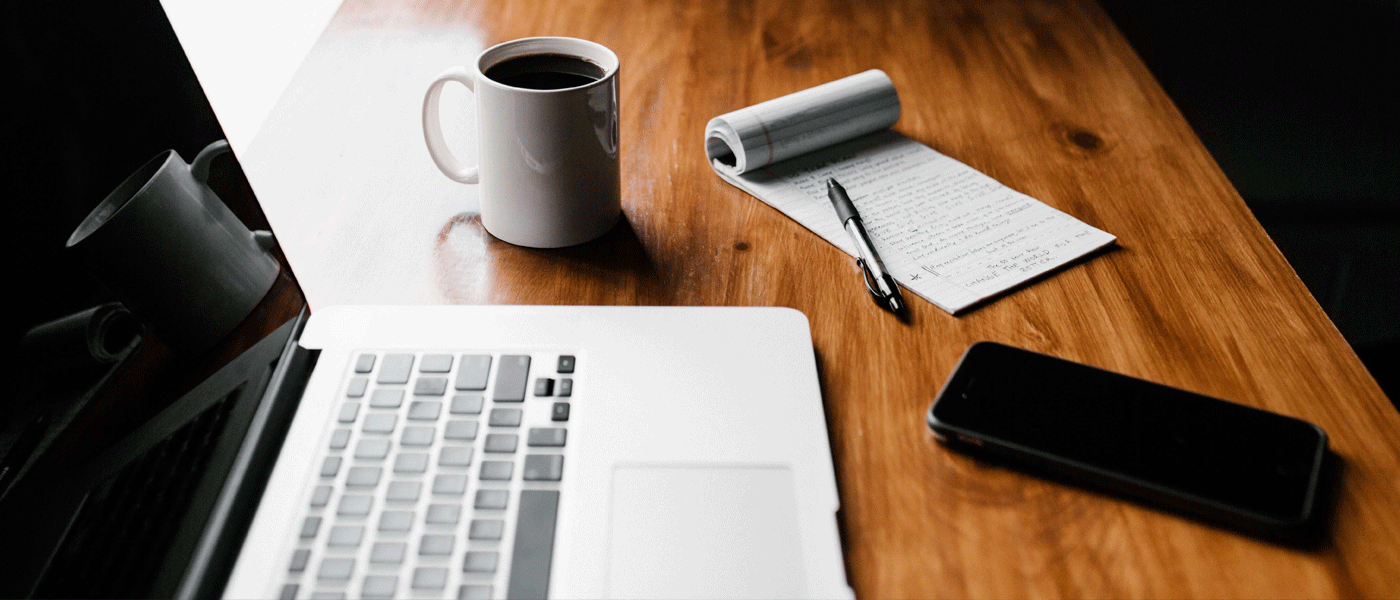 desk with laptop phone and notepad on
