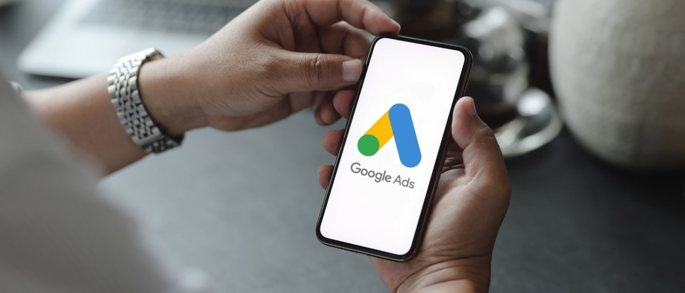 A close up of a person's hands holding a phone with the Google Ads logo