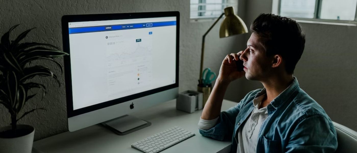 A male marketeer working diligently at a desk, with his attention fixed on a computer screen displaying Facebook Ads revenue.