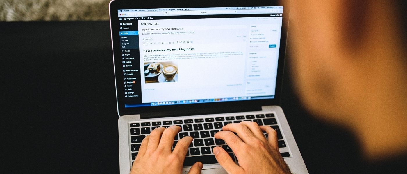 A person engaged in typing on a laptop, with WordPress visible on the screen showing a new blog post being created titled 'How I promote my new blog posts'
